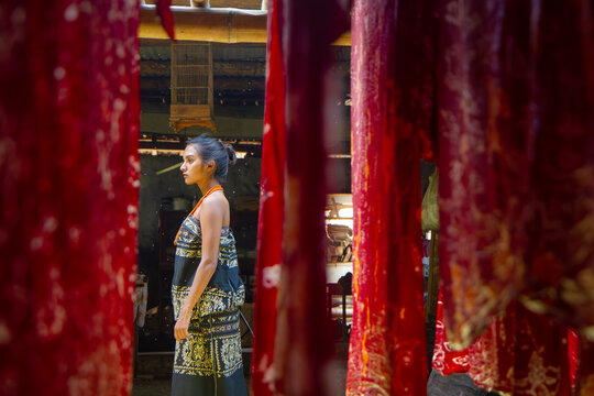 Young Indonesian Woman in Tenun Ikat Between Traditional Dyed Fabrics