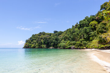 Fototapeta premium Tropical beach on Koh Kradan Island, Thailand. Clear turquoise waters and lush greenery. Sandy shoreline with a scenic coastal landscape.