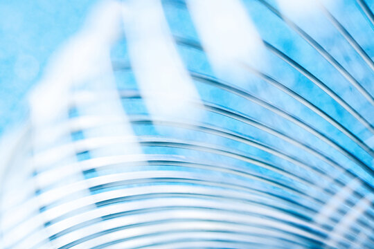 Close-up of shiny metal coils forming a dynamic pattern against bright blue. High-resolution tech background ideal for modern corporate and industrial layout designs. Photo