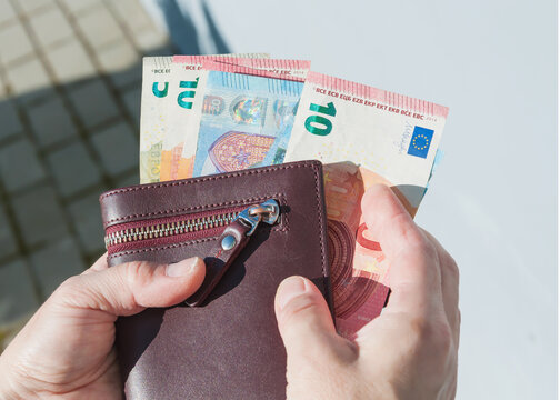 Leather wallet and euro banknotes in a woman's hands, selective focus.	