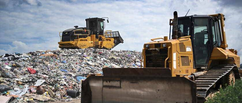 Heavy industrial machinery working at a large landfill site.