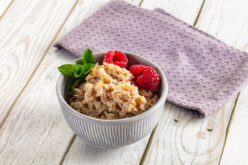 Oatmeal porridge with fresh raspberries and mint in bowl © Andrei Starostin