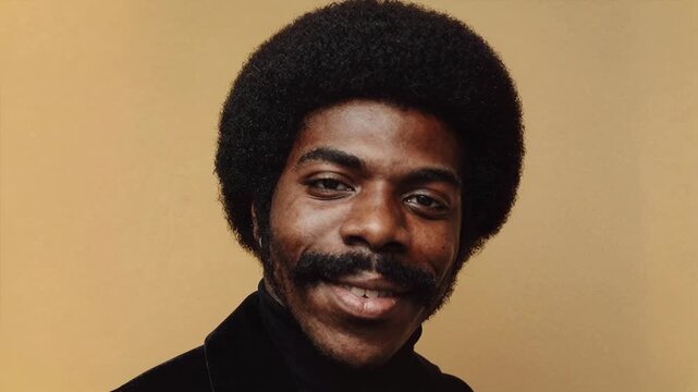 Stylish Black Man with Afro and Mustache Posing Confidently. A charismatic Black man with a distinctive afro hairstyle and mustache smiles warmly