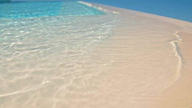 Tranquil turquoise water rippling against a sunlit infinity pool edge with clear blue sky, creating a serene and relaxing summer vacation background concept