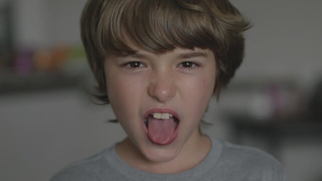 Young Boy Showing Tongue Making Fooling Around, Teasing. Tongue Out Child Grimacing Kid. Angry Boy Shows Her Tongue in Funny Grimace. Bad Behavior of Children.
