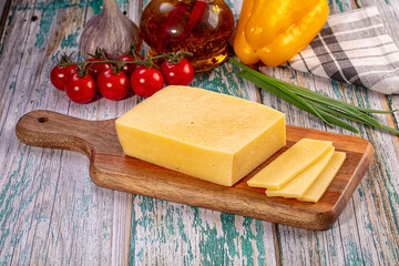 Yellow Cheese Block and Slices on Wooden Board with Fresh Vegetables