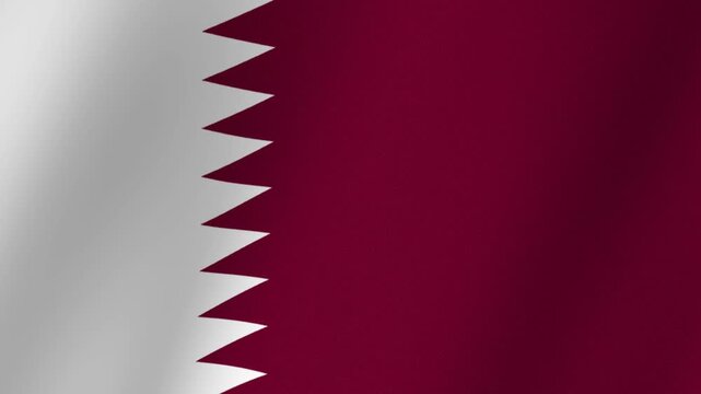 Close up of the national flag of Qatar waving gently in the wind, showcasing its distinct maroon and white serrated pattern