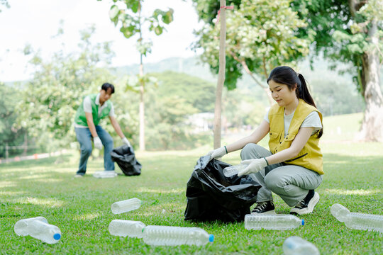 Young volunteers collecting plastic litter from a park lawn, actively promoting environmental protection, ecology, cleanliness, and nature conservation