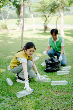 Young volunteers collecting plastic bottles and litter in a park, contributing to environmental conservation, waste reduction, and nature cleanup efforts