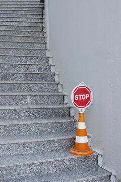 Orange and white road cone with red stop sign on stairs