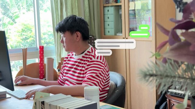 4K shot of a Southeast Asian male teenager sitting in front of a computer monitor, communicating online with animated chat boxes.