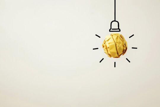 Crumpled yellow paper ball hanging as a light bulb