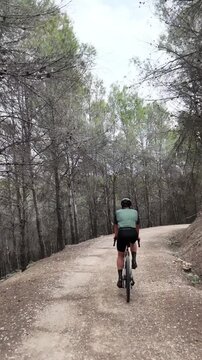 Drone follow shot of gravel biker near forest