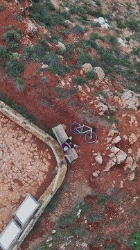 Overhead drone spiral up to resting cyclist on bench