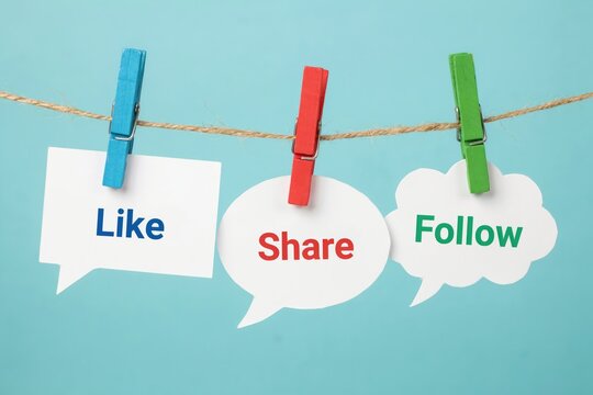 Like, share, and follow speech bubbles hanging on a clothesline