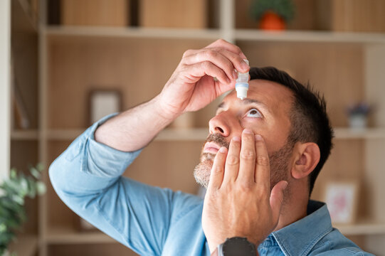 Mature man applying eye drops, treating dry eyes, relieving allergy symptoms, caring for vision health, managing eye irritation, protecting eyesight