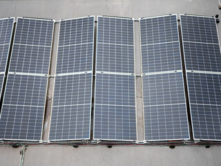 Fototapeta premium Aerial view of photovoltaic solar panels installed on a flat roof. Renewable energy system generating clean electricity for sustainable buildings and businesses. 