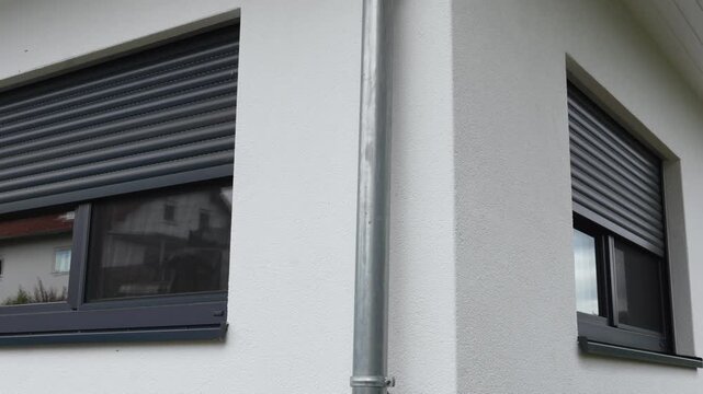 Opening dark security shutters on white facade