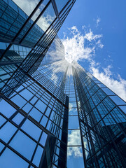 Obraz premium Glass skyscraper reflecting blue sky and clouds.