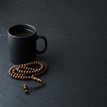 Black coffee mug with Islamic prayer beads tasbih on dark background
