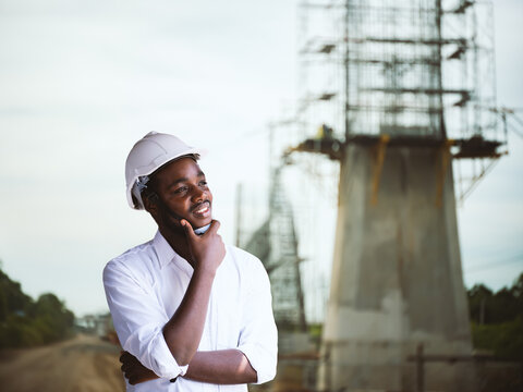 African Civil Engineer Wearing Hardhat Smiling at Infrastructure Construction Site