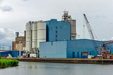 Fototapeta premium Geertruidenberg, The Netherlands, June 11, 2026: predominantly blue and white industrial buildings along the Donge river