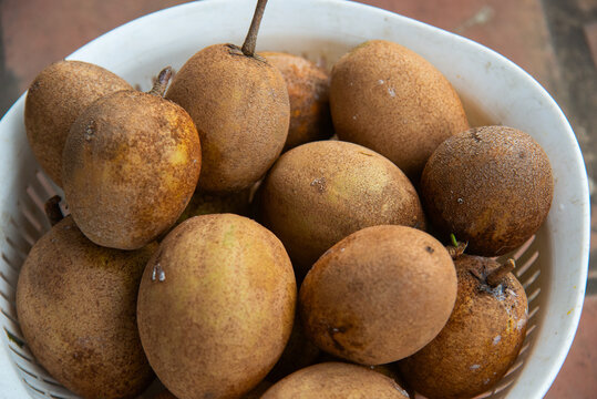 Basket of ripe Manilkara zapota fruits in Vietnam, photographed close-up with brown skin, natural texture, and a fresh local produce appearance.