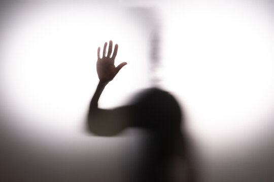 Anonymous man touching frosted glass on white background. Concept of hope 