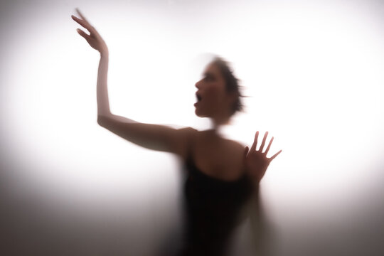 Woman screaming behind frosted glass. Person seeking for help