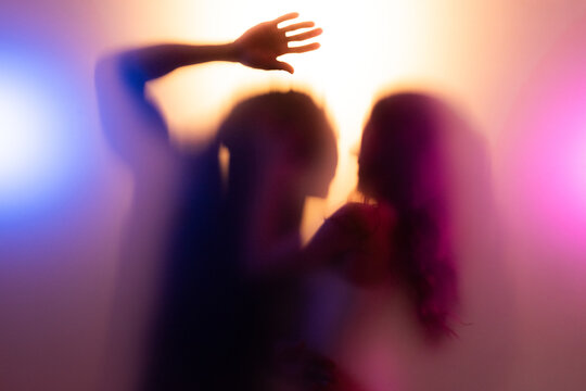 Couple dancing behind frost glass in warm light