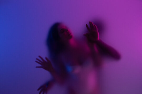 Couple making love behind frosted glass in purple light