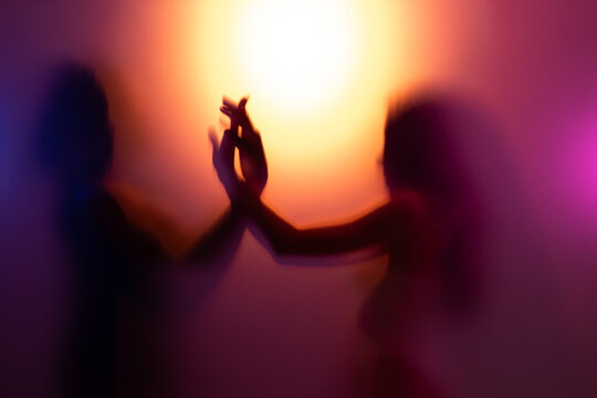 Couple touching each other behind frost glass while dancing together