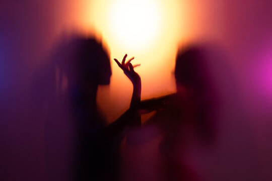 People partying behind frost glass. Woman and man sharing intimate dance together