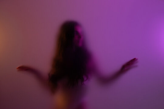 Carefree woman dancing at studio behind frost glass