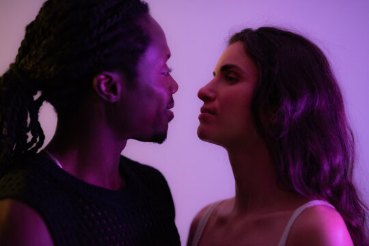 Multiracial couple looking at each other. Studio shot against lilac background