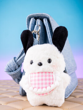 Close-up of a soft dog-shaped keychain  on a  blue bag. Elegant and charming accessory