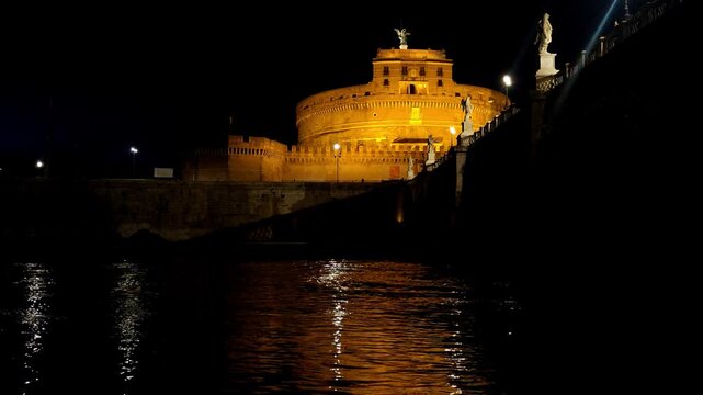 Castel Sant Angelo illuminated at night over the Tiber River.