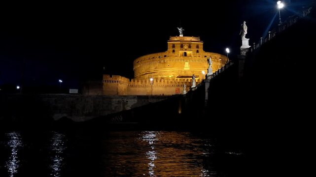 Night panoramic view of Castel Sant Angelo shining over the water.