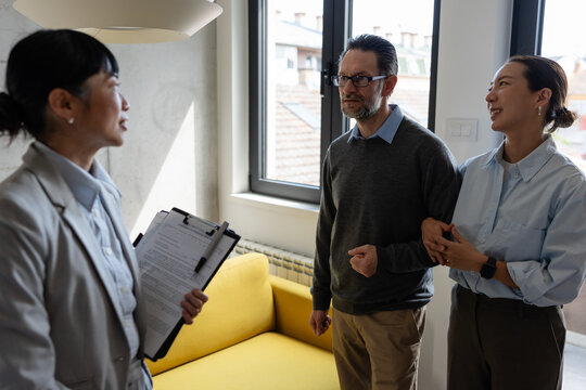 Real estate agent meeting with a multicultural couple during a property consultation. Professional discussion about buying, renting, or investing in a new home.