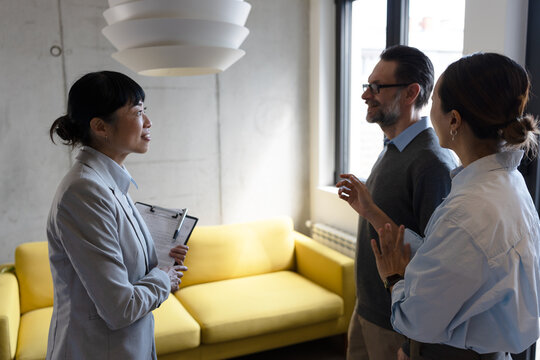 Real estate agent meeting with a multicultural couple during a property consultation. Professional discussion about buying, renting, or investing in a new home