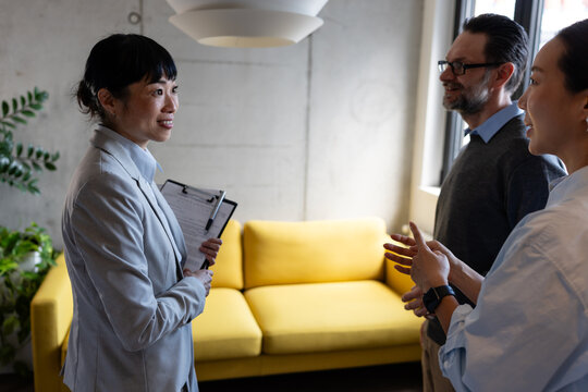 Professional real estate advisor explaining housing options to a mature multicultural couple. Concept of renting, investing, relocation, and property planning