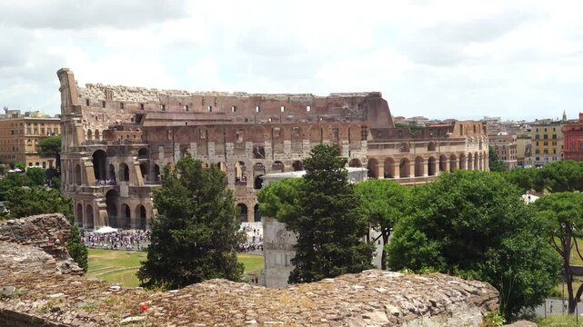 Wide shot of the ancient Colosseum facade with green trees.