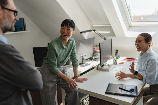 Business professionals exchanging ideas in a relaxed office setting. Innovation, teamwork, workplace communication and collaborative problem solving concept