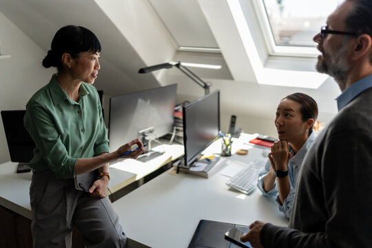 Business professionals exchanging ideas and reviewing projects in contemporary office. Innovation, teamwork, leadership and workplace productivity concept
