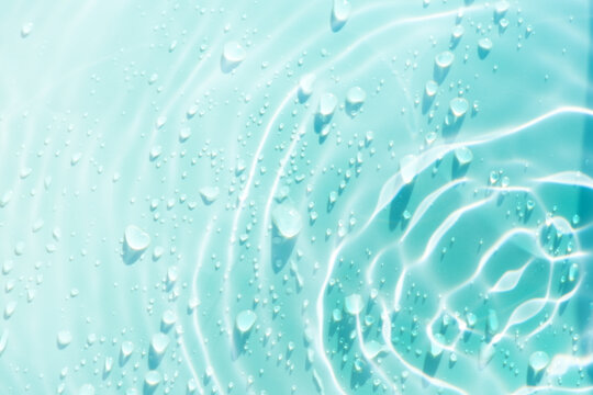 Blue water with ripples on the surface. Defocus blurred transparent blue colored clear calm water surface texture with splashes and bubbles. Water waves with shining pattern texture background.