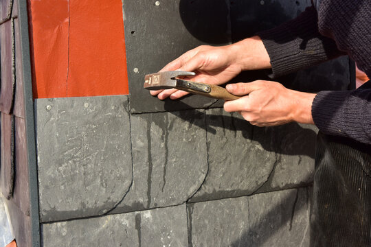 Dachdecker, Schornsteinbauer kleidet neu errichteten Schornstein mit Naturschieferplatten ein, um ihn wetterfest zu machen