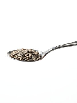 Spoon with small seeds on white background close up