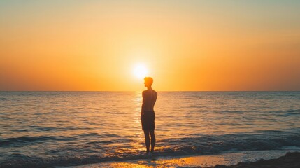 Fototapeta premium Man Standing in Ocean Water at Sunset