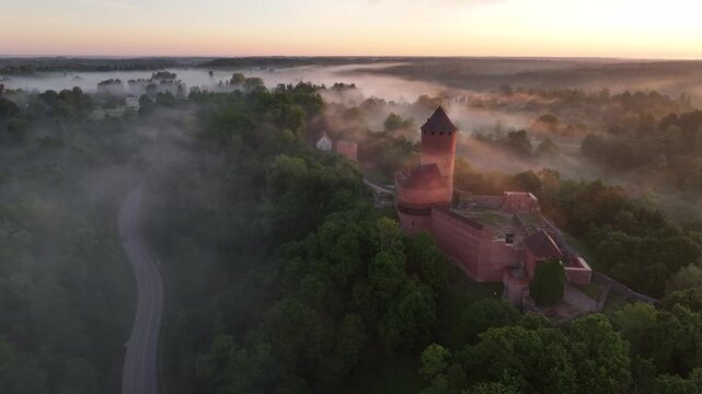 Aerial sunrise over Turaida Castle with golden fog and sun rays in Gauja National Park, Sigulda, Latvia