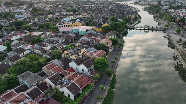 Morning aerial view of Hoi An rooftops and riverside architecture beside a calm canal.